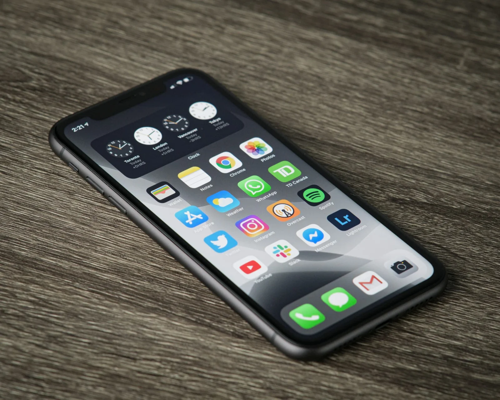 iPhone sobre uma mesa de madeira com aplicativos na tela inicial