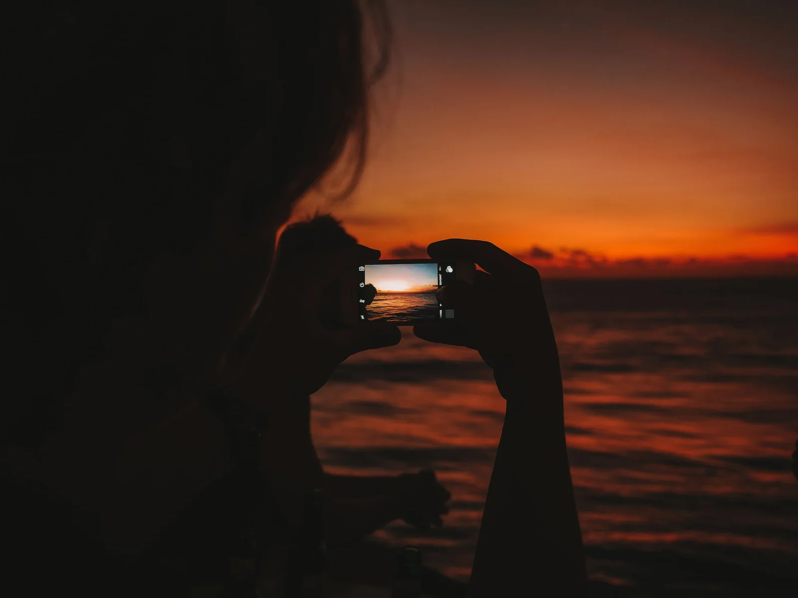 Pessoa fotografando o pôr do sol com smartphone